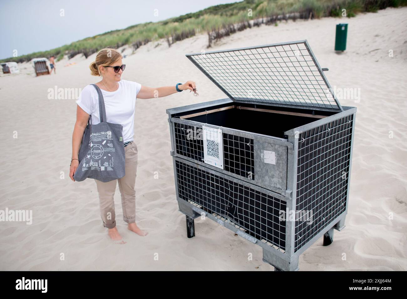 Spiekeroog, Deutschland. Juni 2024. Nadine Weber, Projektkoordinatorin für Nachhaltigkeit und Klimaschutz auf Spiekeroog, steht mit einem Strandmüllbeutel an einer Strandmüllkiste auf der Insel. Spiekeroogs umweltfreundliche und nachhaltige Ausrichtung soll weiter gestärkt werden und die Insel langfristig klimaneutral werden. Quelle: Hauke-Christian Dittrich/dpa/Alamy Live News Stockfoto