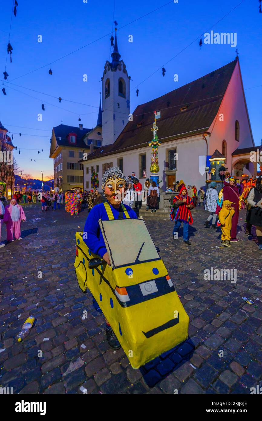 Luzern, Schweiz - 20. Februar 2023: Menschen in Kostümen und anderen Menschenmengen, in der Nähe der Peterskapelle, bei Sonnenaufgang, Teil des Fasnacht Karnevals, in Stockfoto