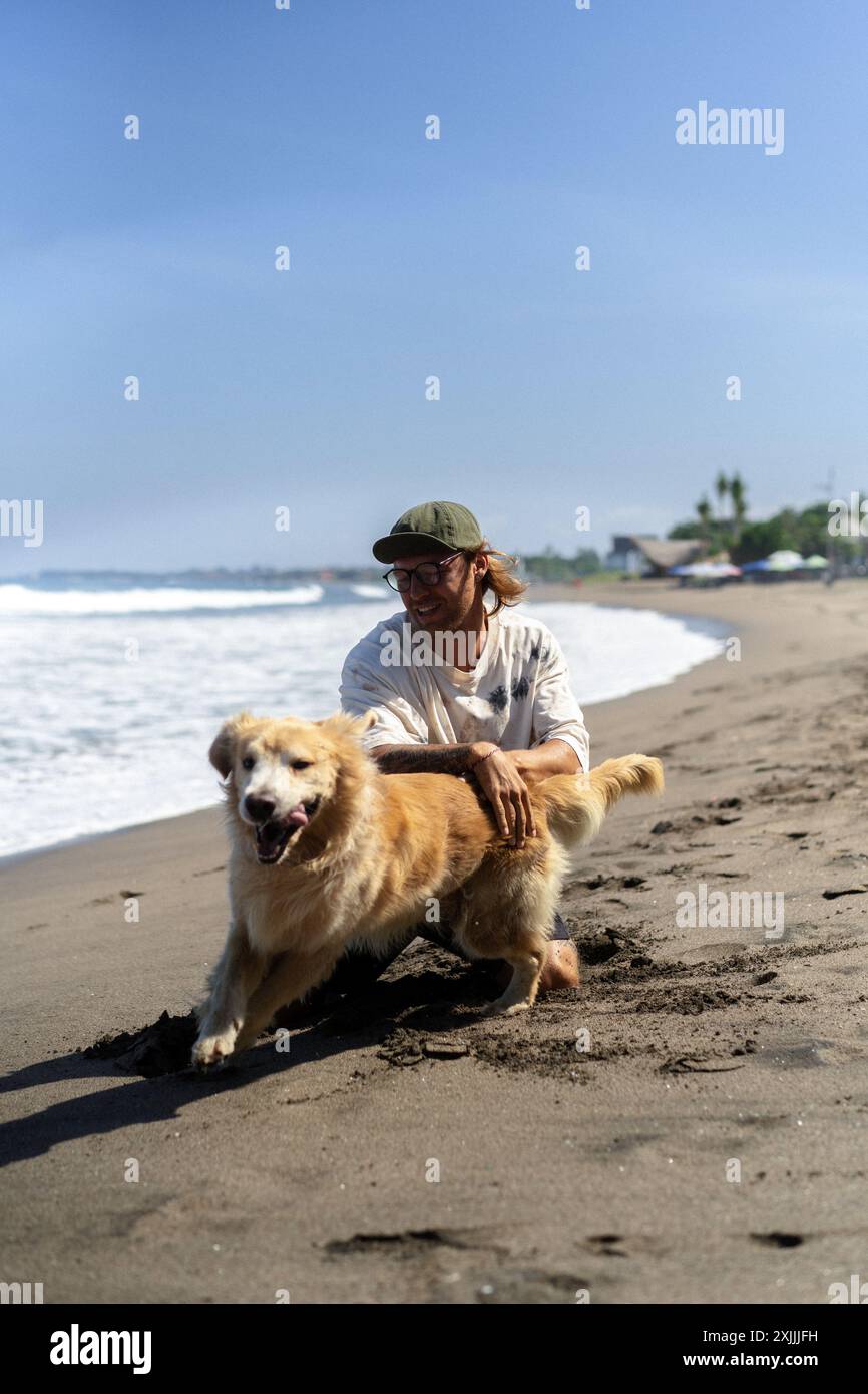 Mann spielt am Strand mit Retriever-Hund, rennt und täuscht herum. Stockfoto