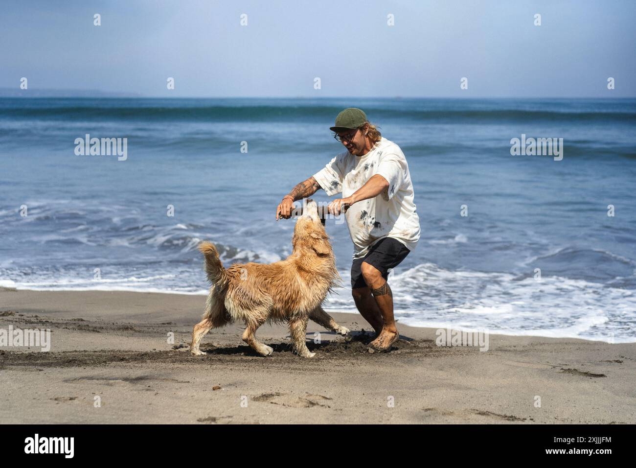Mann spielt am Strand mit Retriever-Hund. Stockfoto