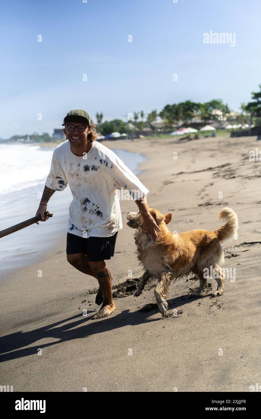 Mann spielt am Strand mit Retriever-Hund, rennt und täuscht herum. Stockfoto
