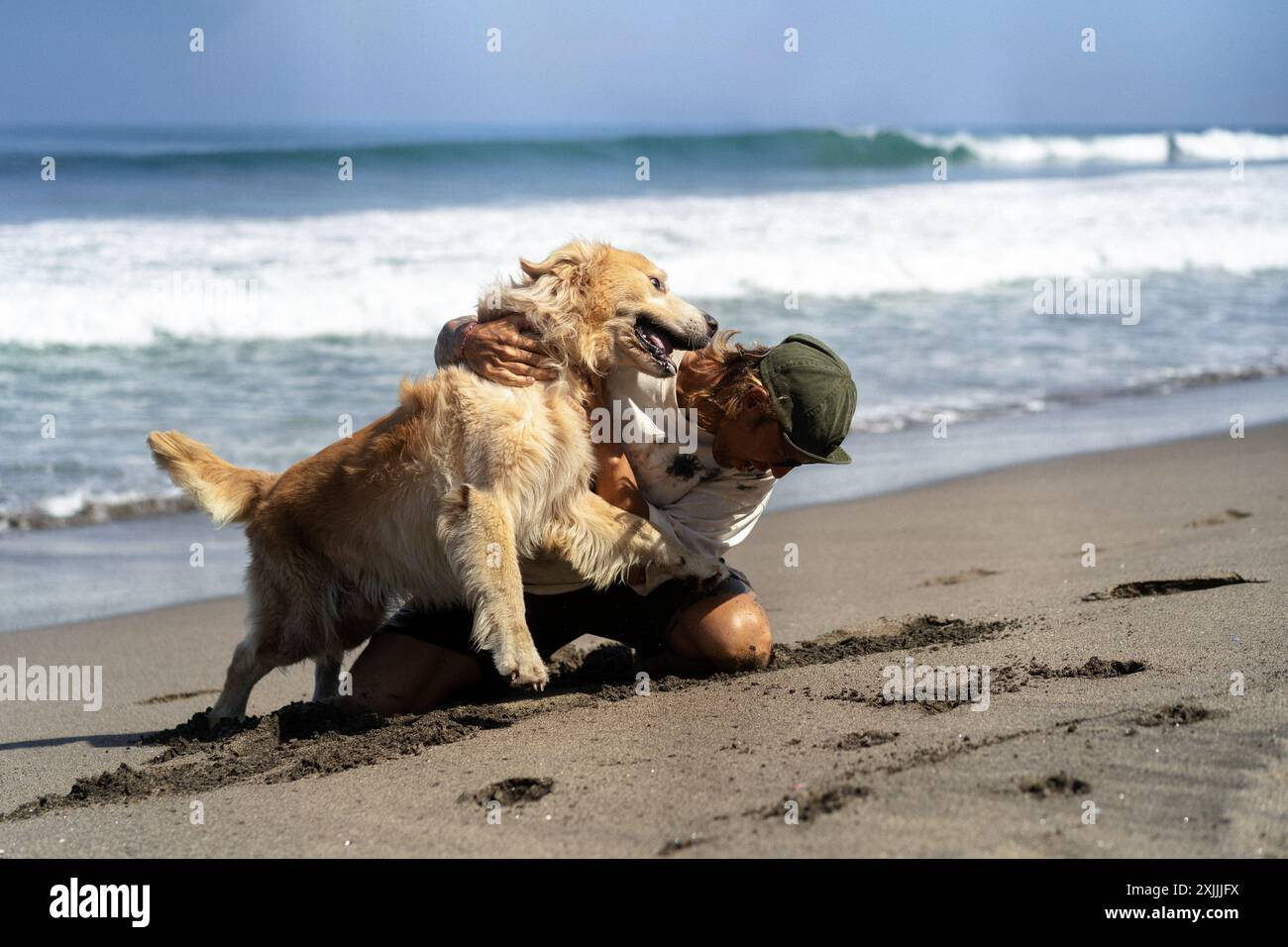 Mann spielt am Strand mit Retriever-Hund, rennt und täuscht herum. Stockfoto