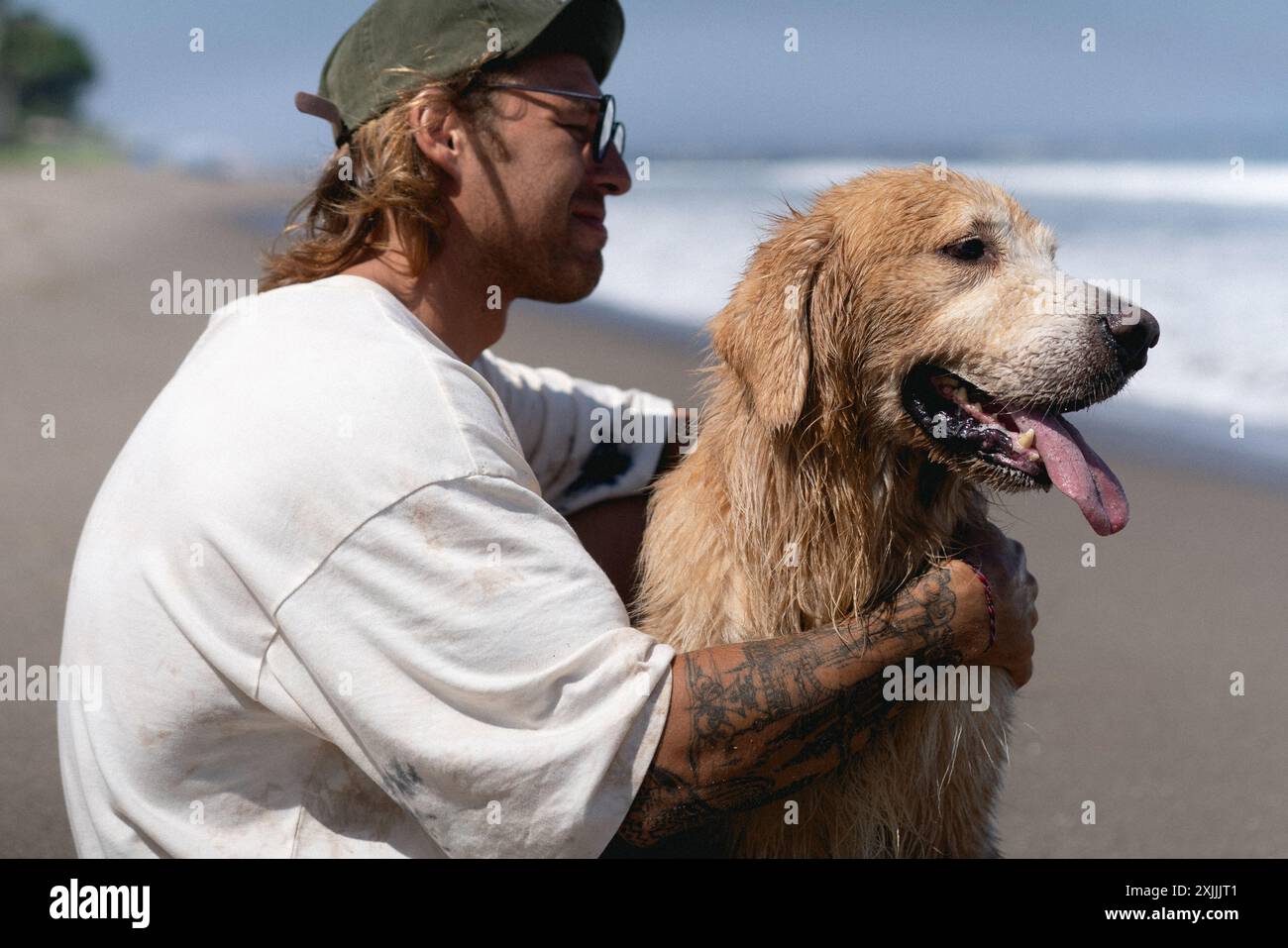 Mann am Strand mit Retriever-Hund. Stockfoto
