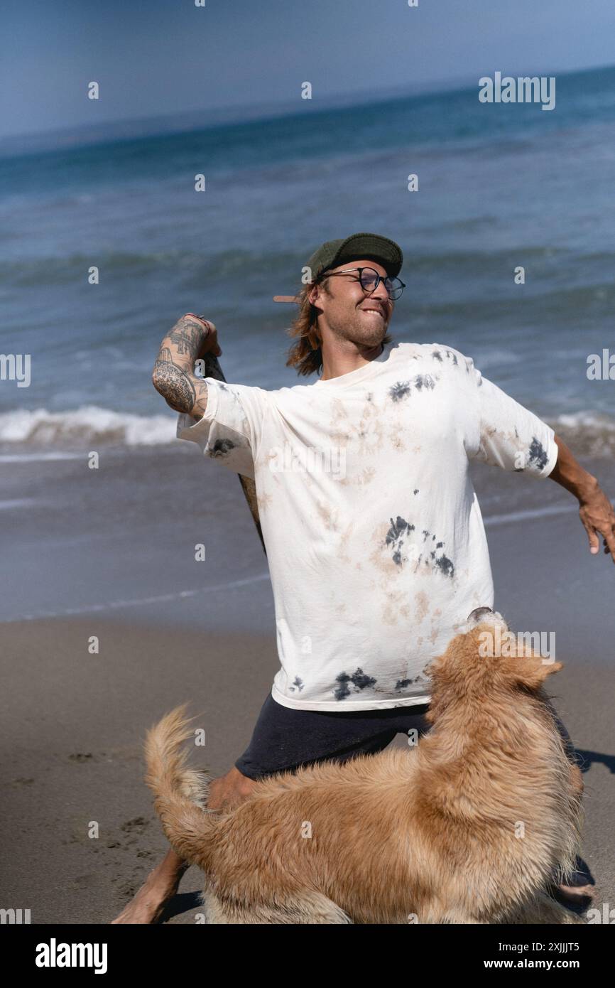 Mann spielt am Strand mit Retriever-Hund, sie rennen und täuschen herum. Stockfoto