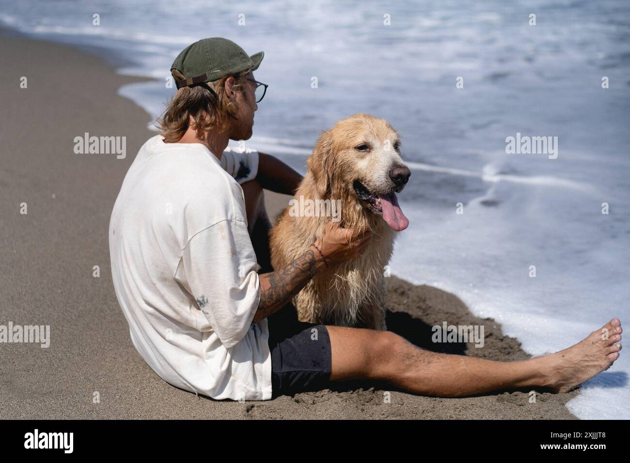 Mann am Strand mit Retriever-Hund. Stockfoto