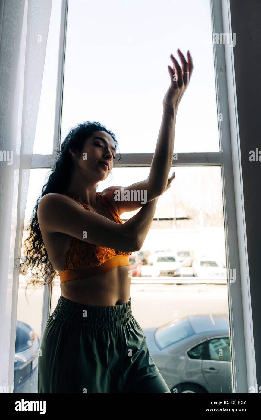 Frau tanzt anmutig vor einem Fenster Stockfoto