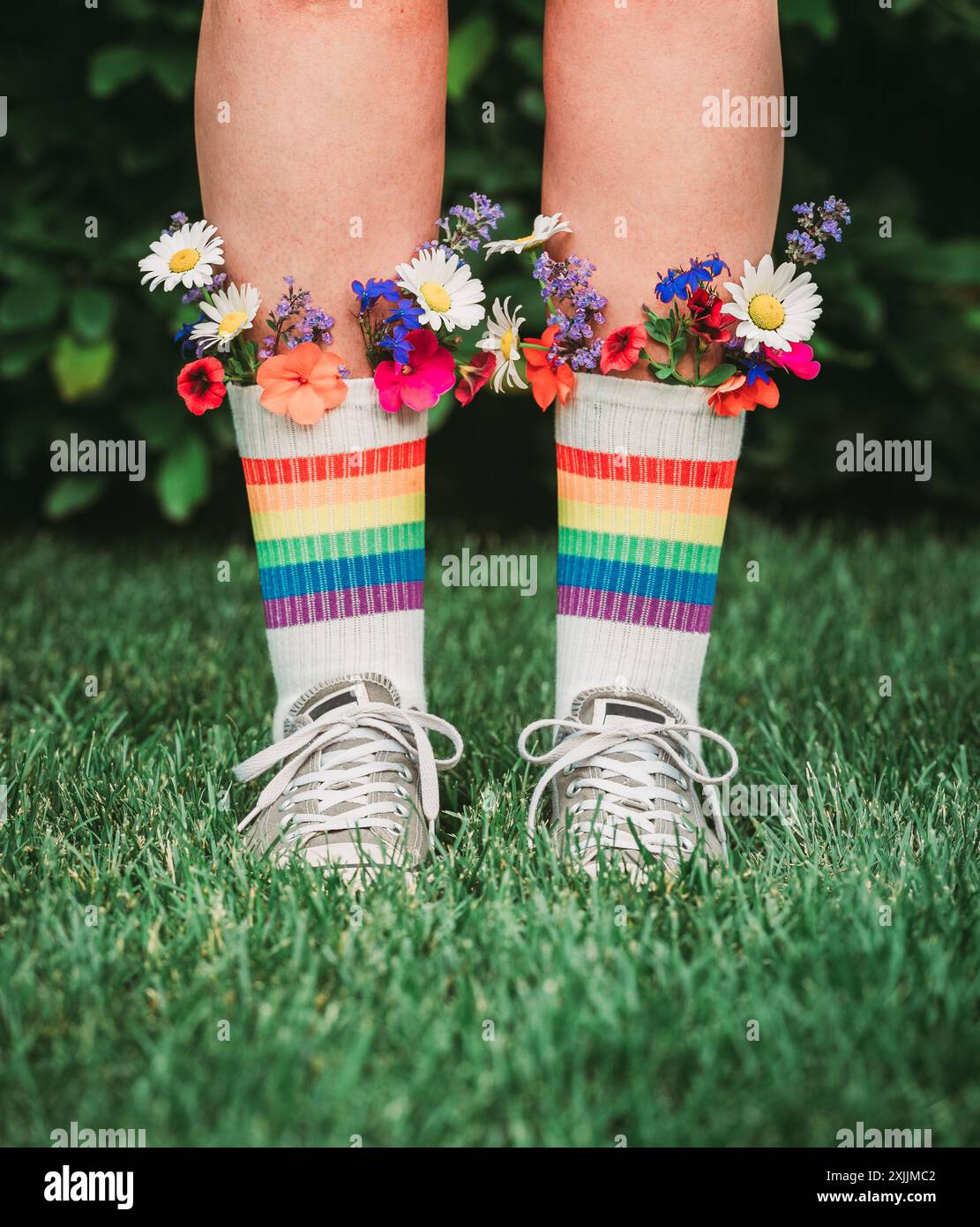 Beine in Regenbogensocken mit bunten Blumen im Oberteil für LGBTQ+ Stockfoto