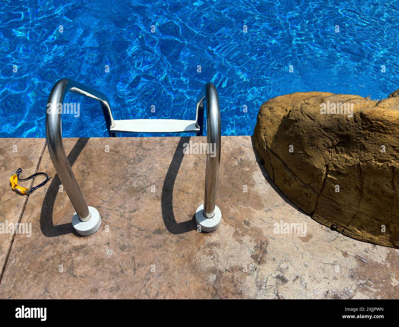 Swimmingpool Leiter mit Schutzbrille und Felsen auf der Poolterrasse Stockfoto