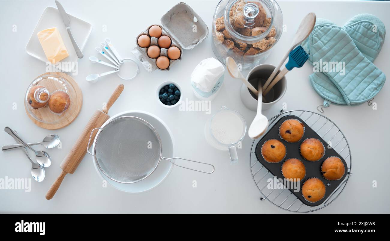 Mehl, Eier und Butter auf dem Tisch zum Backen, Kuchen und Dessert im Haus mit Blick von oben, Milch und Zucker. Pulver, Schneebesen und Muffin auf der Küchenzeile Stockfoto