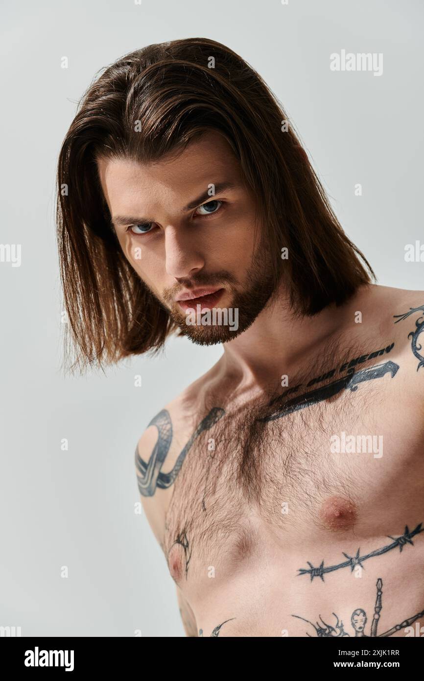 Kaukasischer Mann mit langen Haaren zeigt Brusttattoos. Stockfoto