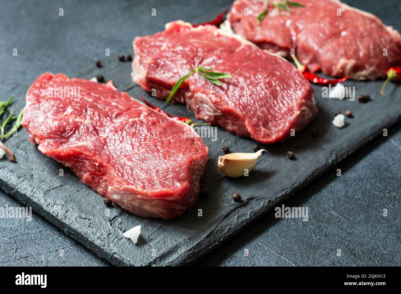Rohes Rindersteak auf Steinbrett mit Thymian und Paprika, Metzgerkonzept Stockfoto