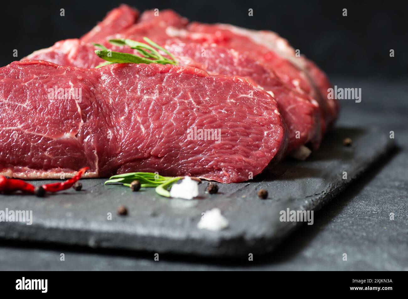 Rohes Rindersteak auf Steinbrett mit Thymian und Paprika, Metzgerkonzept Stockfoto
