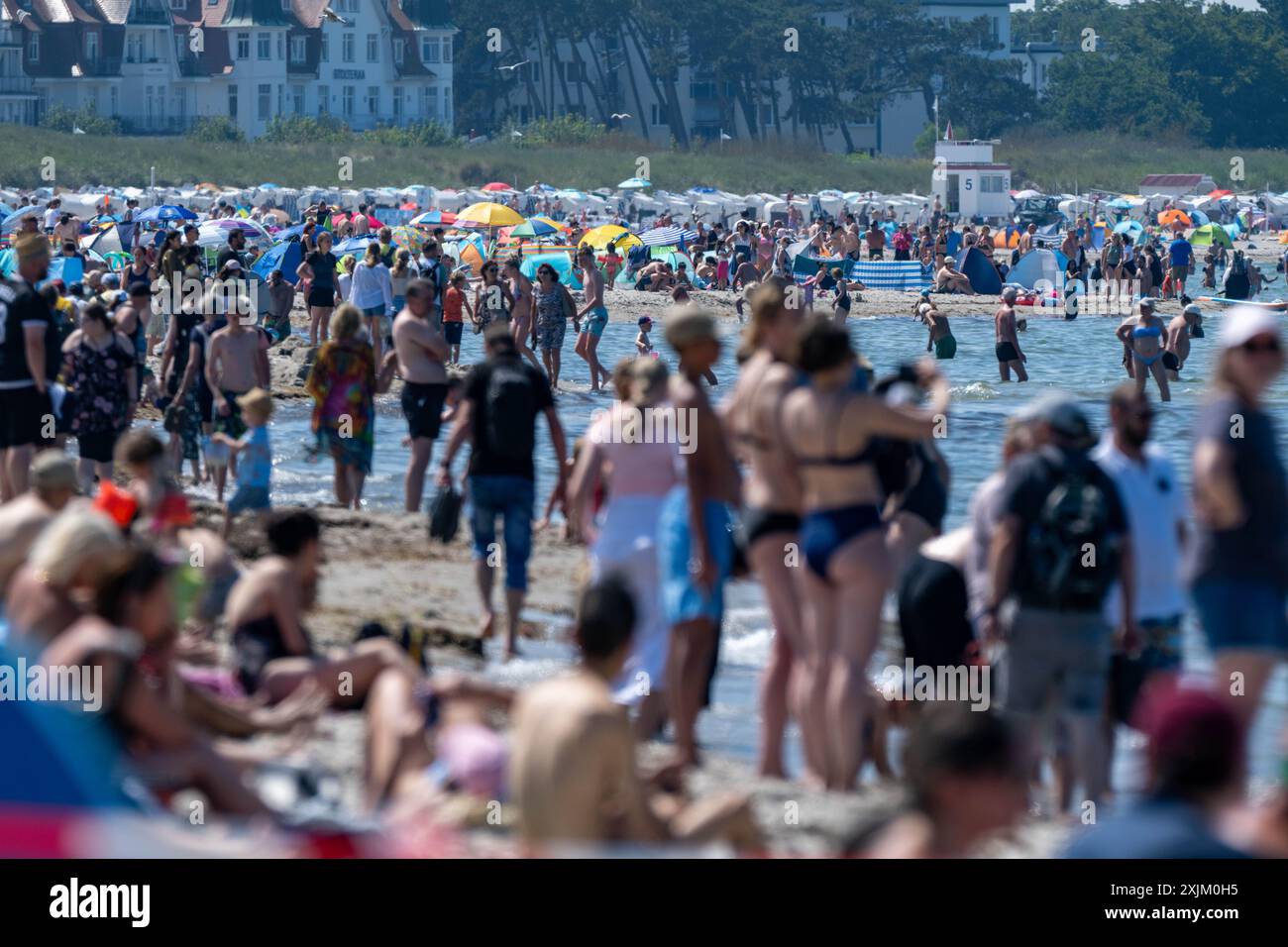 19. Juli 2024, Mecklenburg-Vorpommern, Warnemünde: Touristen spazieren und schwimmen am Ostseestrand. Foto: Stefan sauer/dpa Stockfoto