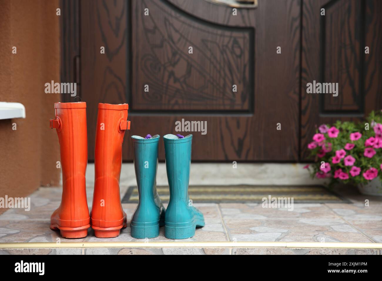 Zwei Paar Gummistiefel vor der Tür in der Nähe des Eingangs im Freien Stockfoto