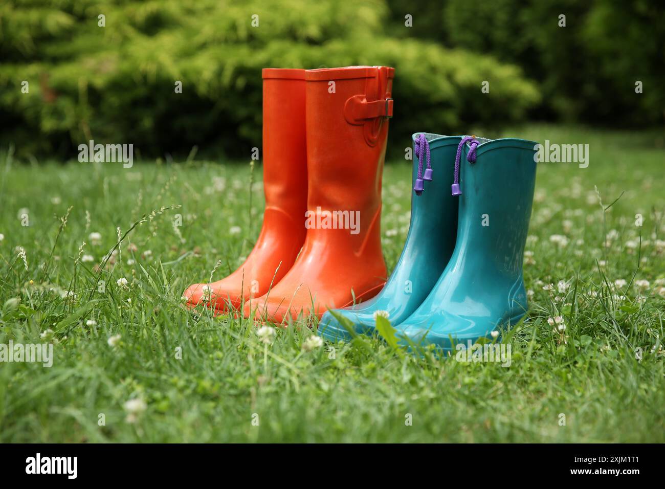 Zwei Paar Gummistiefel auf grünem Gras im Freien Stockfoto