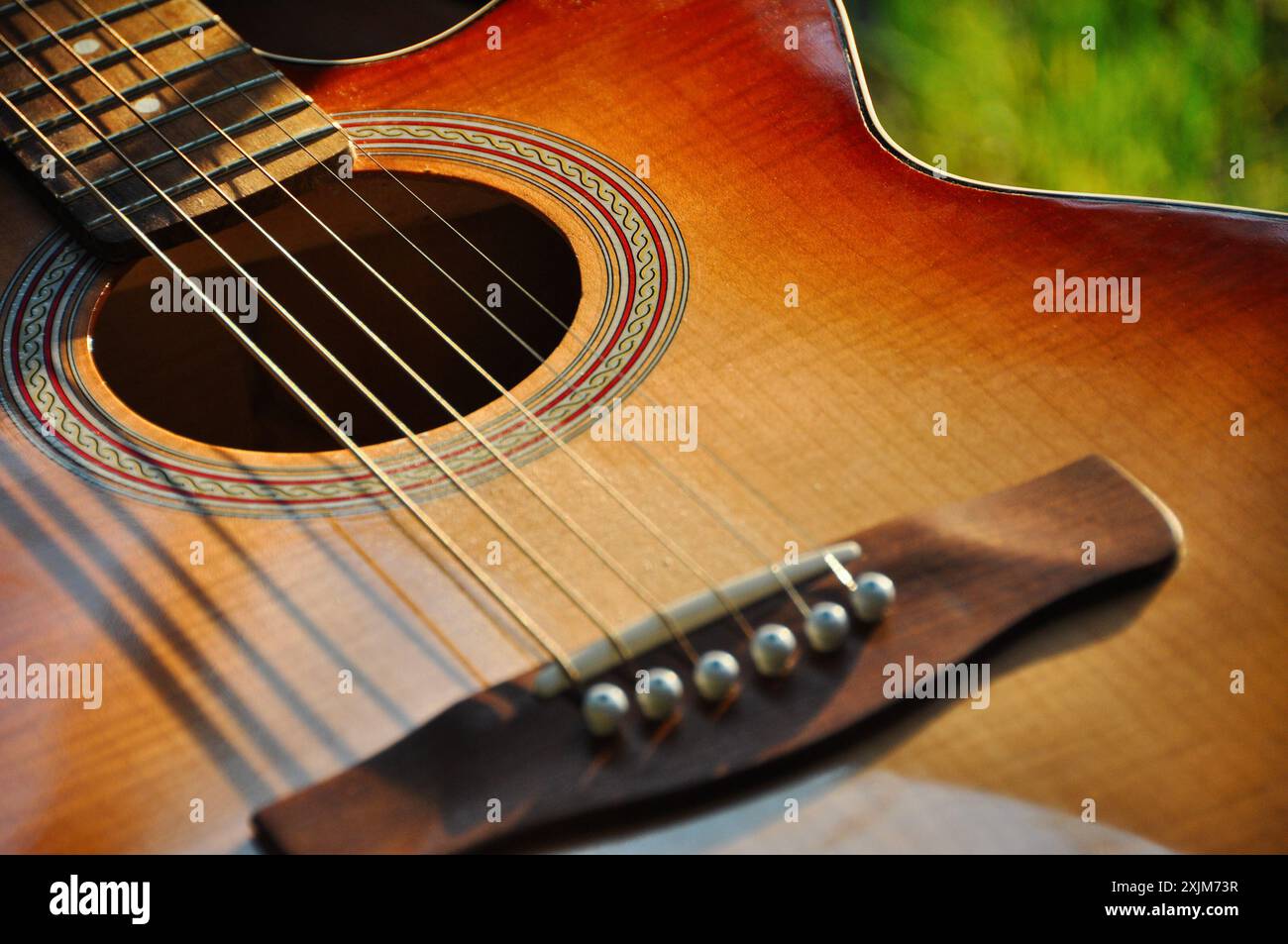 Akustikgitarre. Nahaufnahme einer alten Akustikgitarre im Garten: Glänzendes braunes Deck-Instrument mit Metall- und Nylonsaiten über Griffbrett. Stockfoto