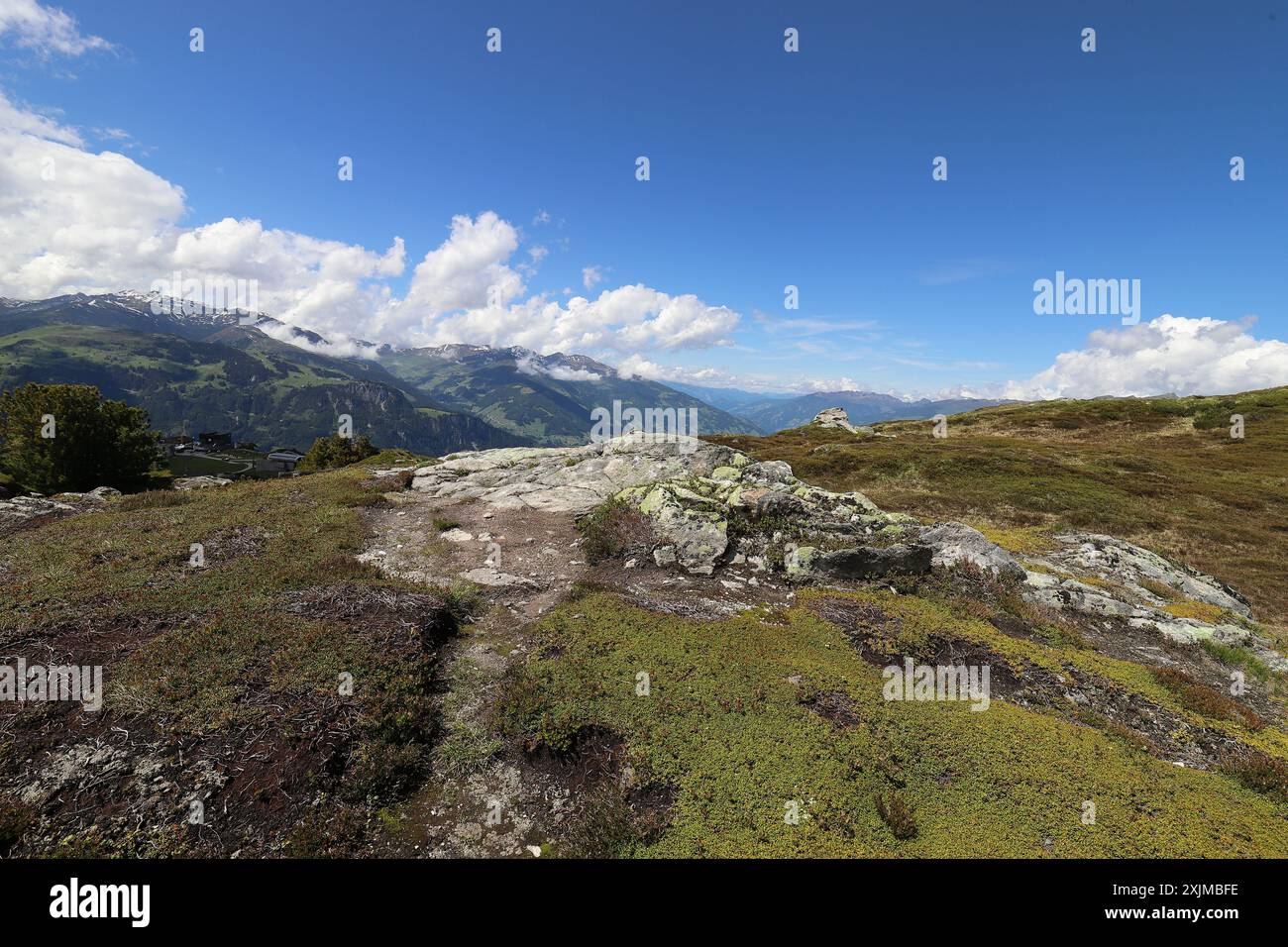 Blick über ein grünes Hochplateau auf Bergketten im Hintergrund unter einem bewölkten blauen Himmel, Weitwinkelblick Stockfoto