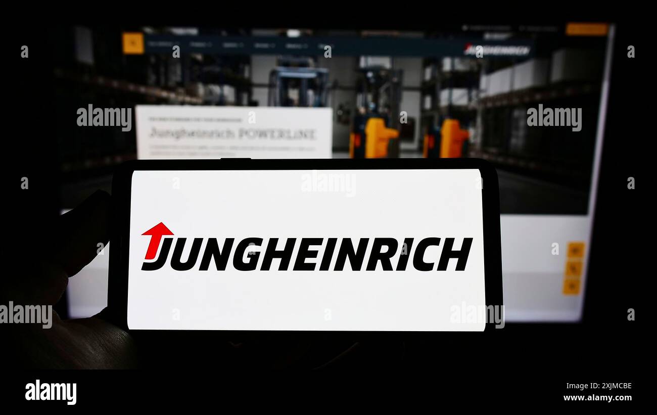 Stuttgart, 21.05.2022: Handybesitzer mit Logo des deutschen Maschinenbauunternehmens Jungheinrich AG auf dem Bildschirm vor dem Geschäft Stockfoto