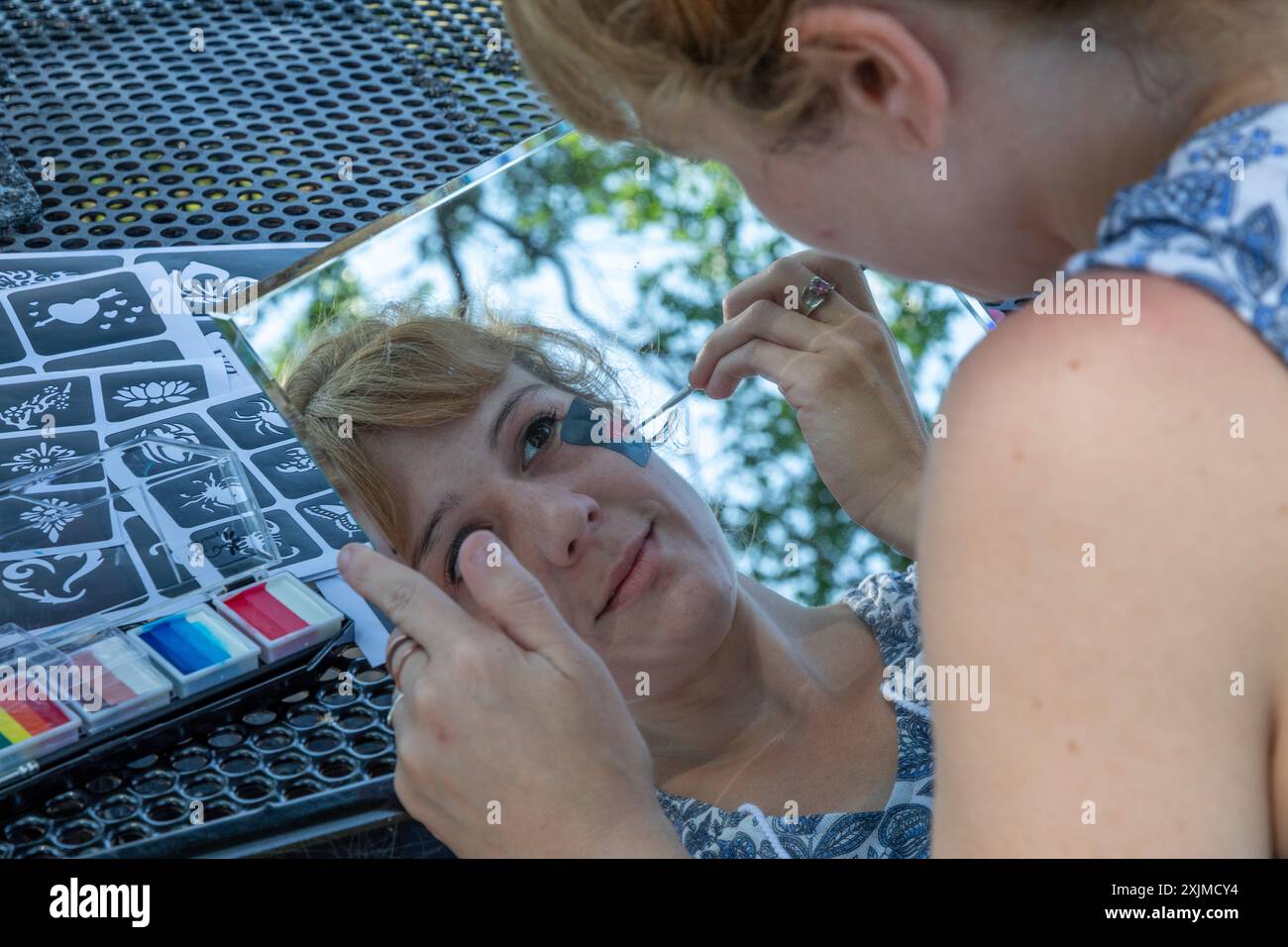 Detroit, Michigan – Eine Frau verwendet einen Spiegel, um ihr Gesicht beim jährlichen „Summer Sizzler“-Picknick und -Party von zwei Detroit Neighborho zu malen Stockfoto