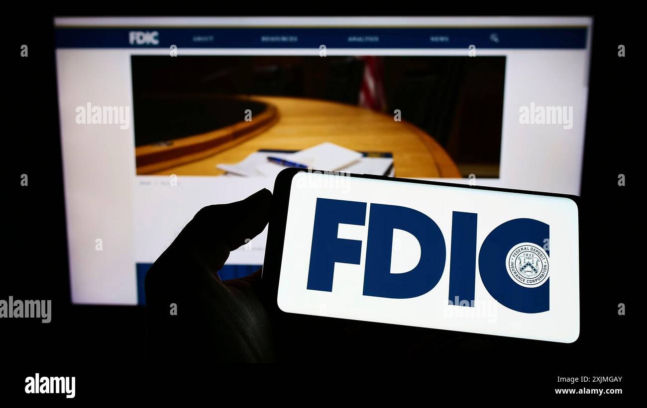 Stuttgart, Deutschland, 10.07.2022: Person mit Mobiltelefon mit Logo der US Federal Deposit Insurance Corporation (FDIC) auf dem Bildschirm vor der Webseite. Stockfoto