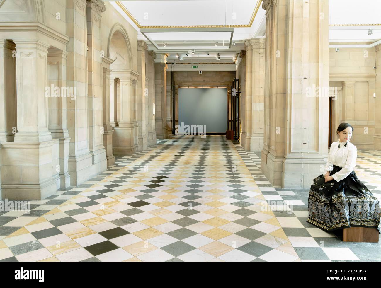 Chinesin sitzt in einem Museumsflur mit kariertem Boden und Säulen, Edinburgh, Schottland Stockfoto