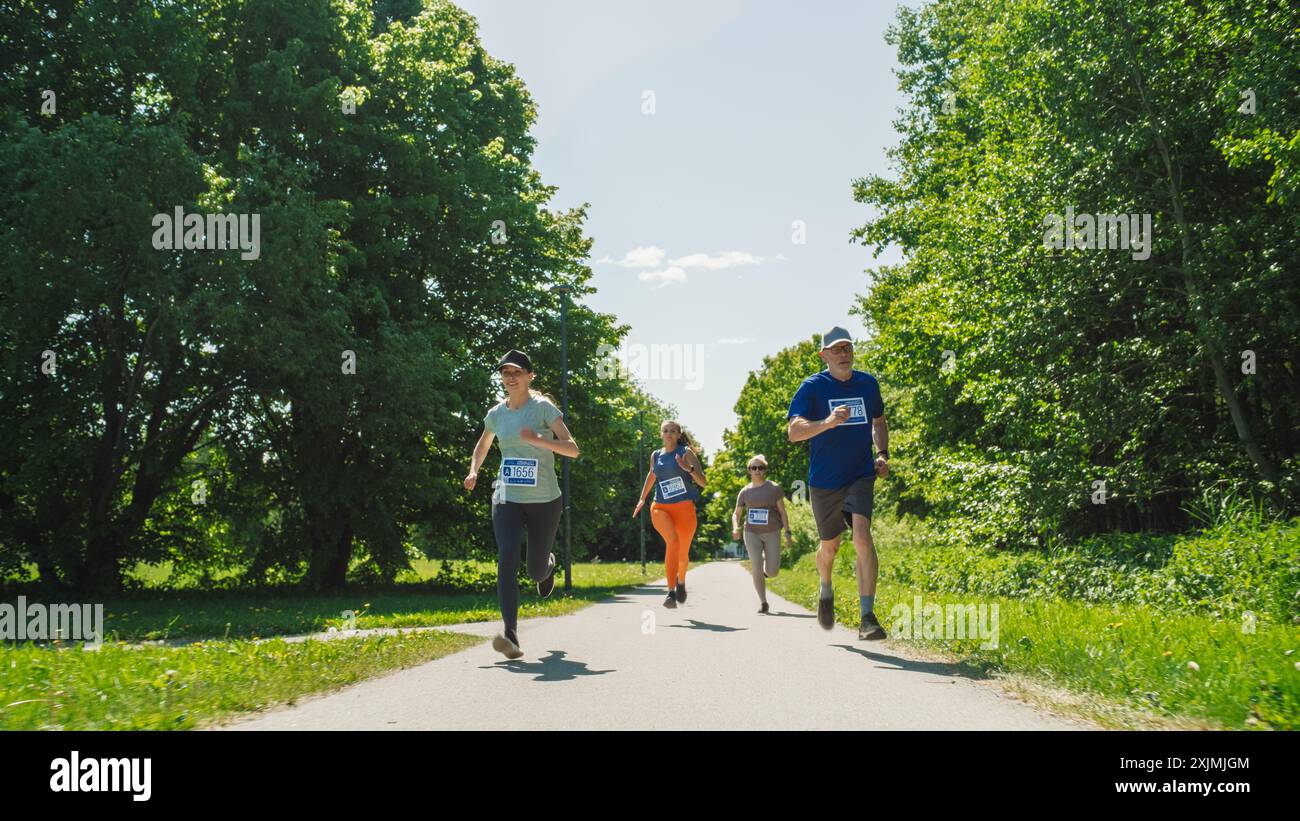 Porträt einer Gruppe von Personen, die gemeinsam an einem Marathon teilnehmen und durch einen Park Trail laufen. Jogger geben ihr Bestes, um die Ziellinie in einem freundlichen Rennen zu erreichen Stockfoto
