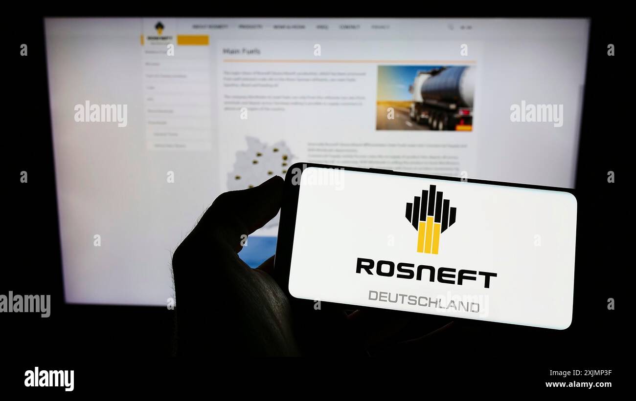 Stuttgart, 25.09.2022: Person, die ein Mobiltelefon mit dem Logo des Ölraffinerieunternehmens Rosneft Deutschland GmbH auf dem Bildschirm vor der Webseite hält. Stockfoto