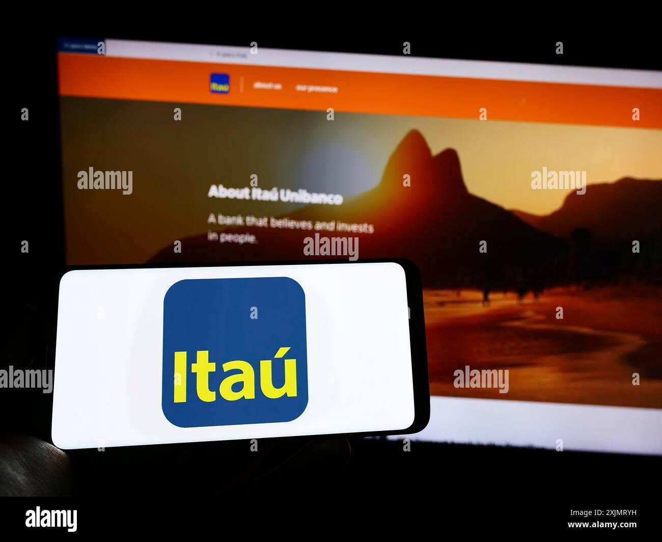 Stuttgart, 14.10.2022: Person, die ein Mobiltelefon mit dem Logo des brasilianischen Unternehmens Itau Unibanco Holding SA auf dem Bildschirm vor dem Geschäft hält Stockfoto