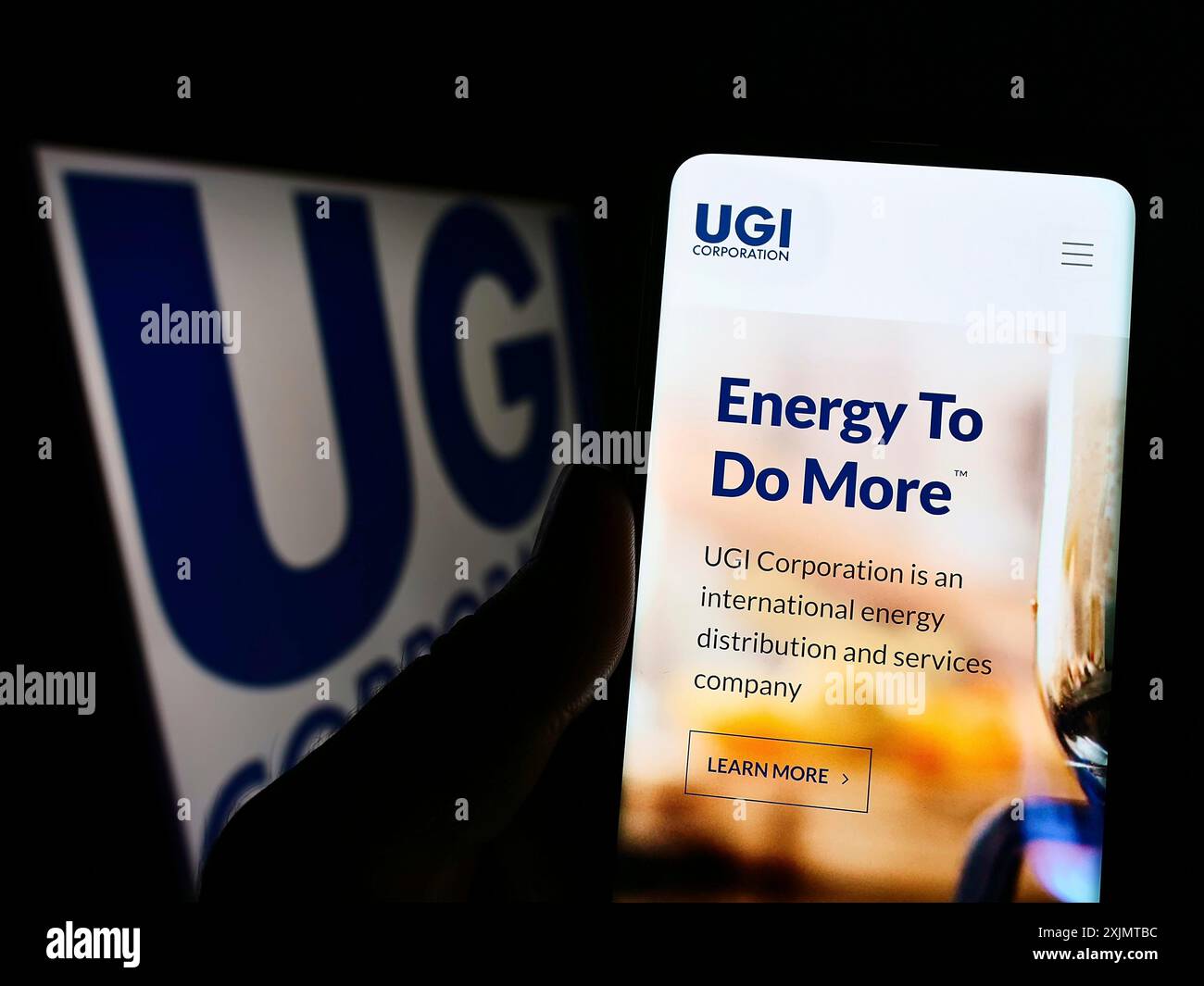 Stuttgart, 18.10.2022: Person, die ein Mobiltelefon hält, mit Webseite des US-Energieunternehmens UGI Corporation vor dem Firmenlogo. Fokus Stockfoto