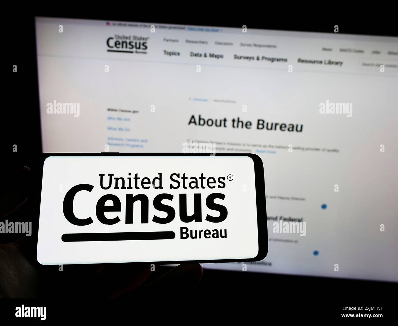 Stuttgart, 23.10.2022: Person, die ein Mobiltelefon mit dem Logo der US-amerikanischen Behörde United States Census Bureau (USCB) auf dem Bildschirm vor der Webseite hält. Stockfoto