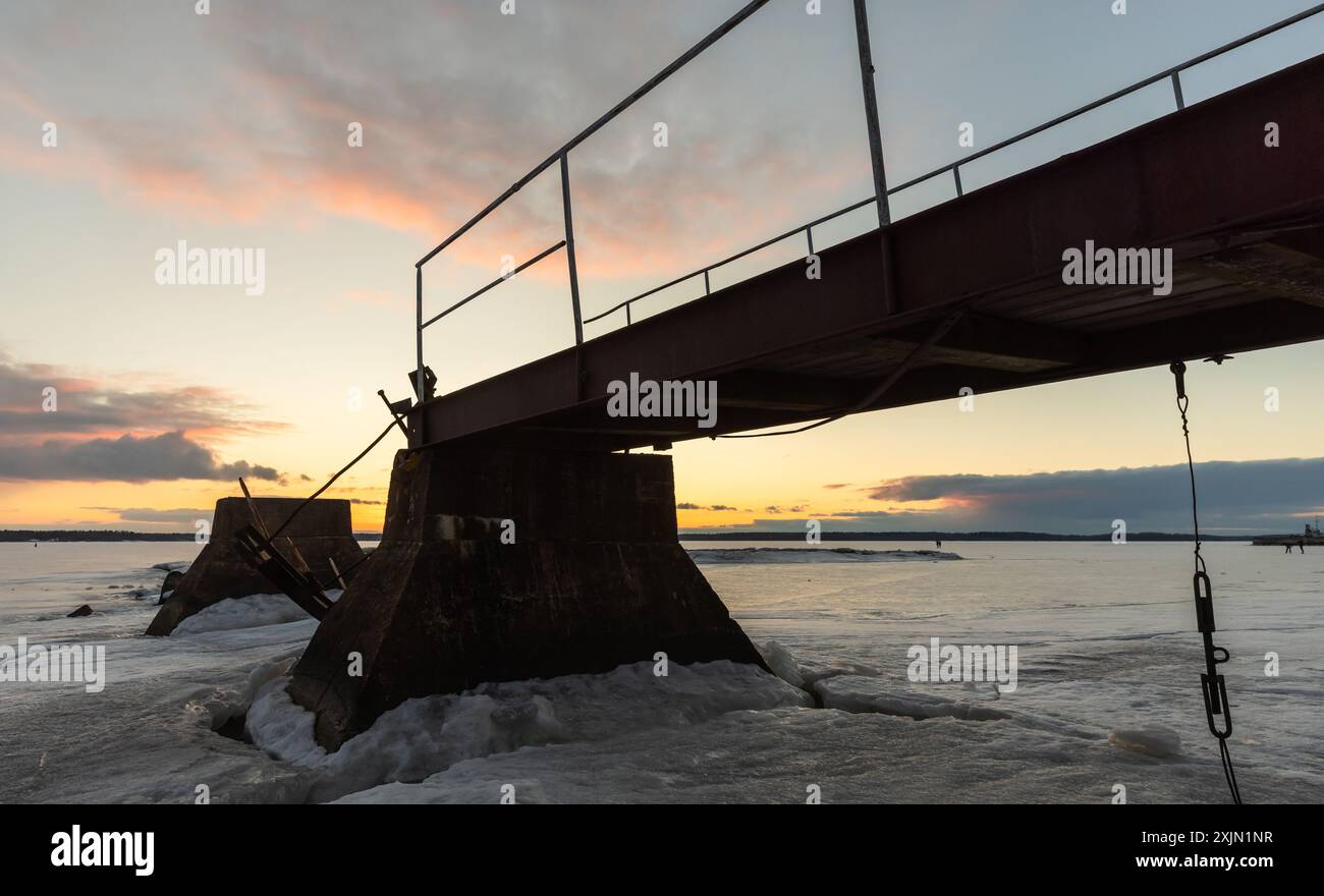 Die alte, kaputte Pier-Silhouette ist unter Sonnenuntergang, Winterlandschaft Stockfoto