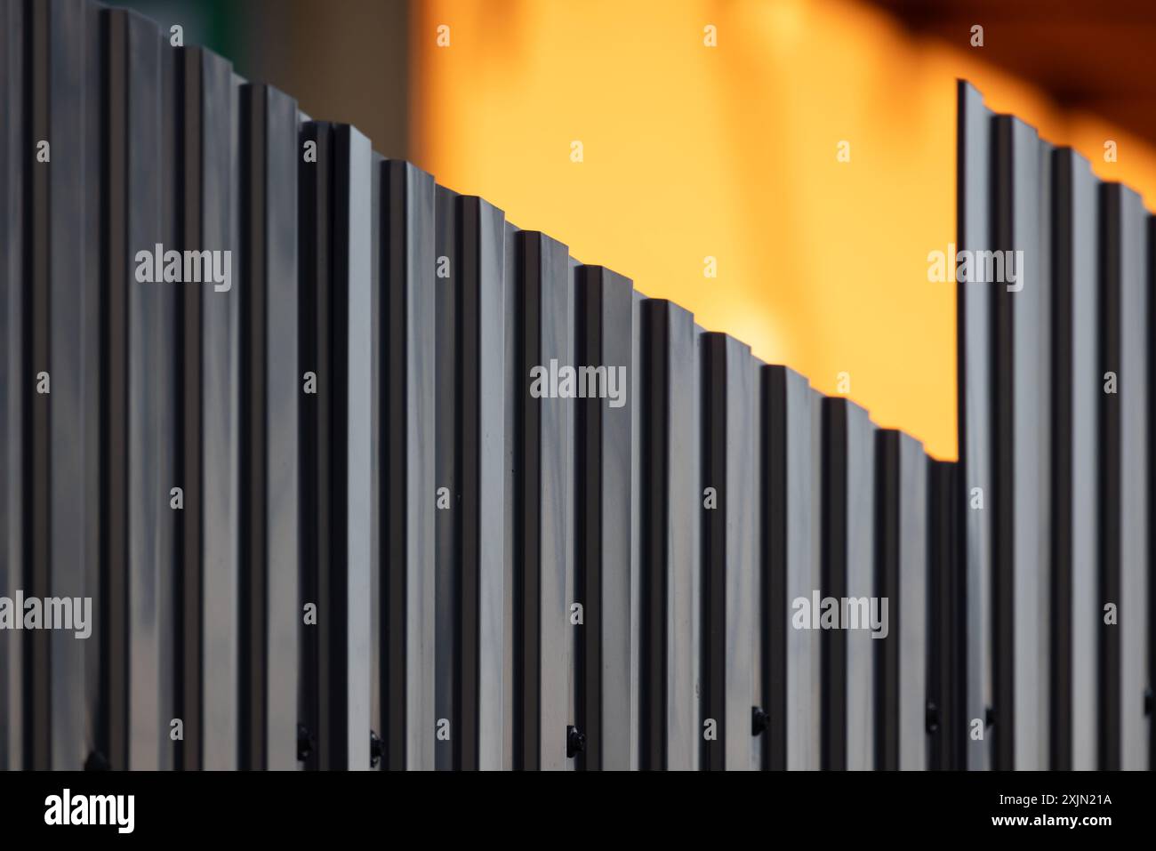 Glänzend geriffelter grauer Metallzaun, abstraktes Hintergrundfoto mit selektivem Weichfokus Stockfoto