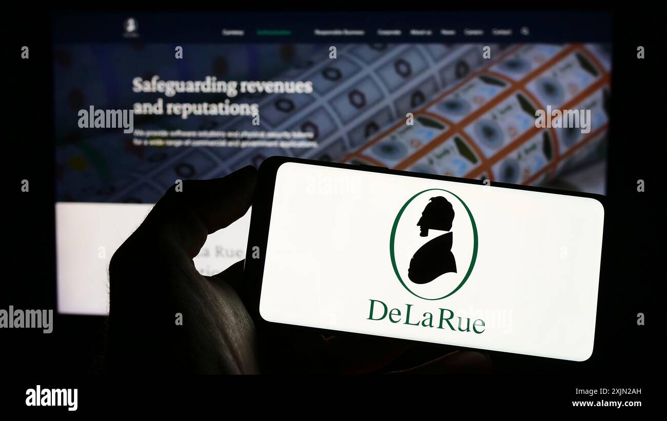 Stuttgart, Deutschland, 01-30-2023: Person, die ein Mobiltelefon mit dem Logo des britischen Banknotenherstellers de La Rue plc auf dem Bildschirm vor der Website der Geschäftswelt hält. Stockfoto