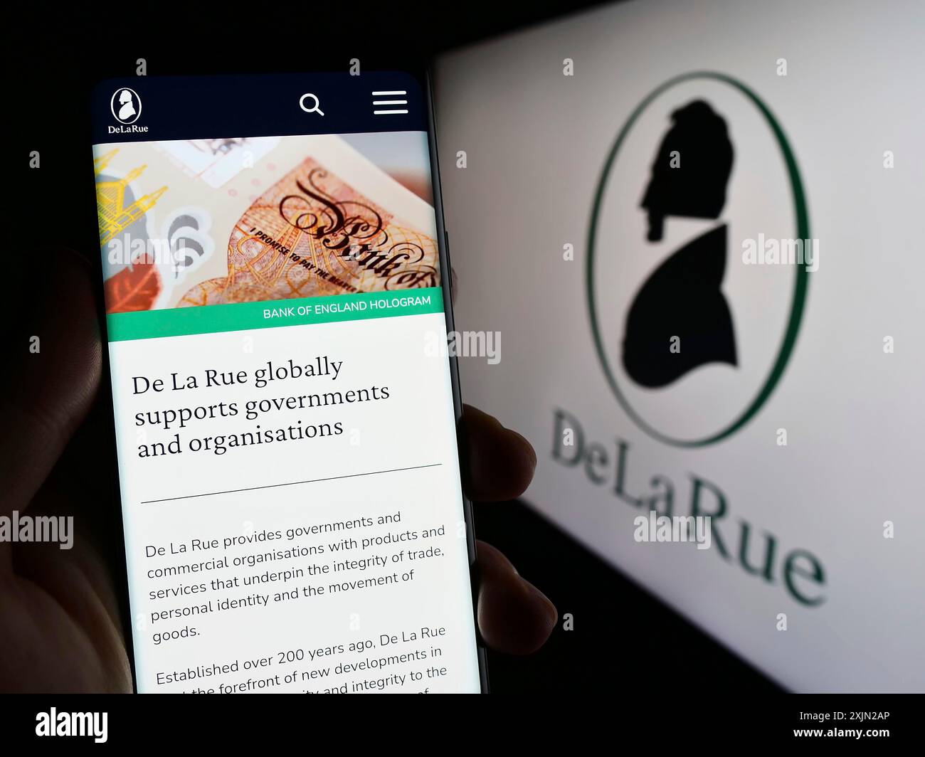 Stuttgart, Deutschland, 01-30-2023: Person, die ein Mobiltelefon hält, mit Webseite des britischen Banknotenherstellers de La Rue plc auf dem Bildschirm mit Firmenlogo. Fokus Stockfoto