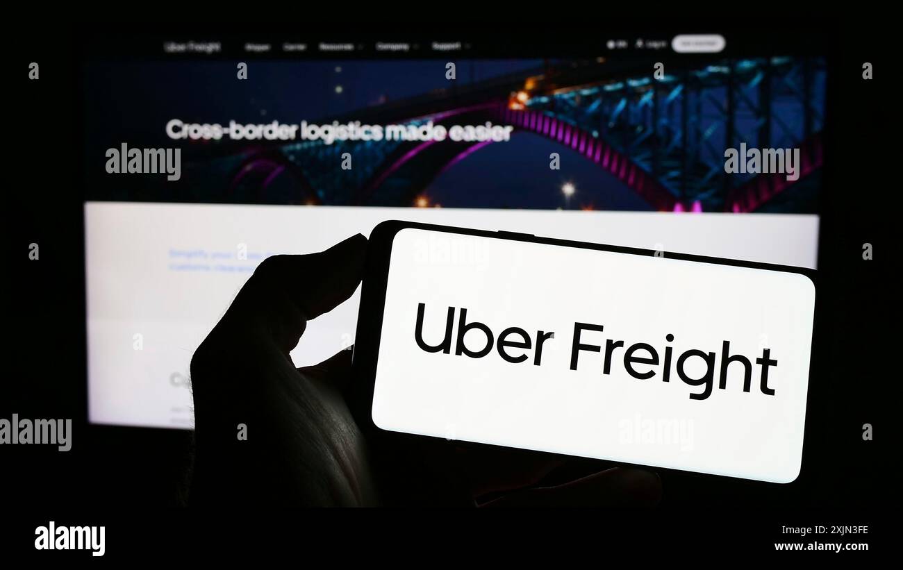 Stuttgart, Deutschland, 18.03.2023: Person, die ein Mobiltelefon mit dem Logo des US-Logistikunternehmens Uber Freight auf dem Bildschirm vor der Business-Website hält. Fokus Stockfoto