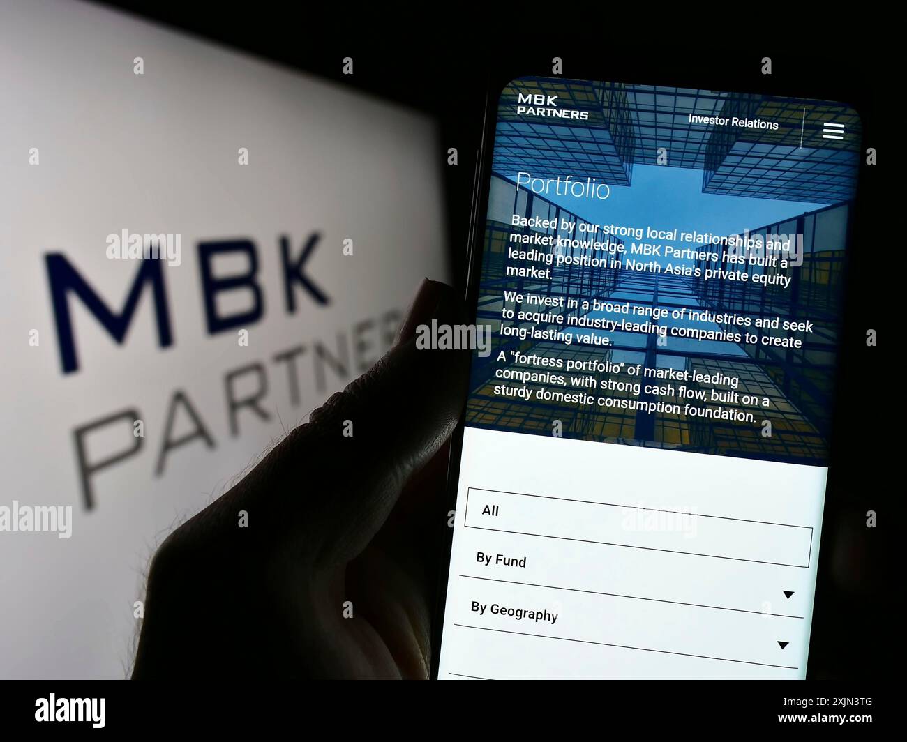 Stuttgart, Deutschland, 22.03.2023: Person, die ein Mobiltelefon hält, mit Webseite der koreanischen Investmentgesellschaft MBK Partners Ltd. Auf dem Bildschirm vor dem Logo. Stockfoto