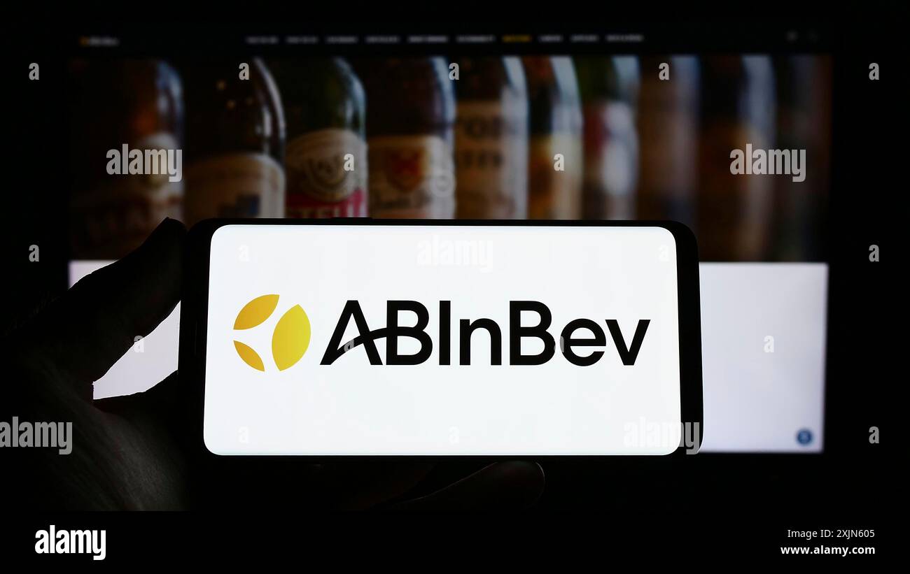 Stuttgart, Deutschland, 04.04.2023: Person, die ein Smartphone mit dem Logo der Brauerei Anheuser-Busch InBev (ab InBev) auf dem Bildschirm vor der Website hält. Stockfoto