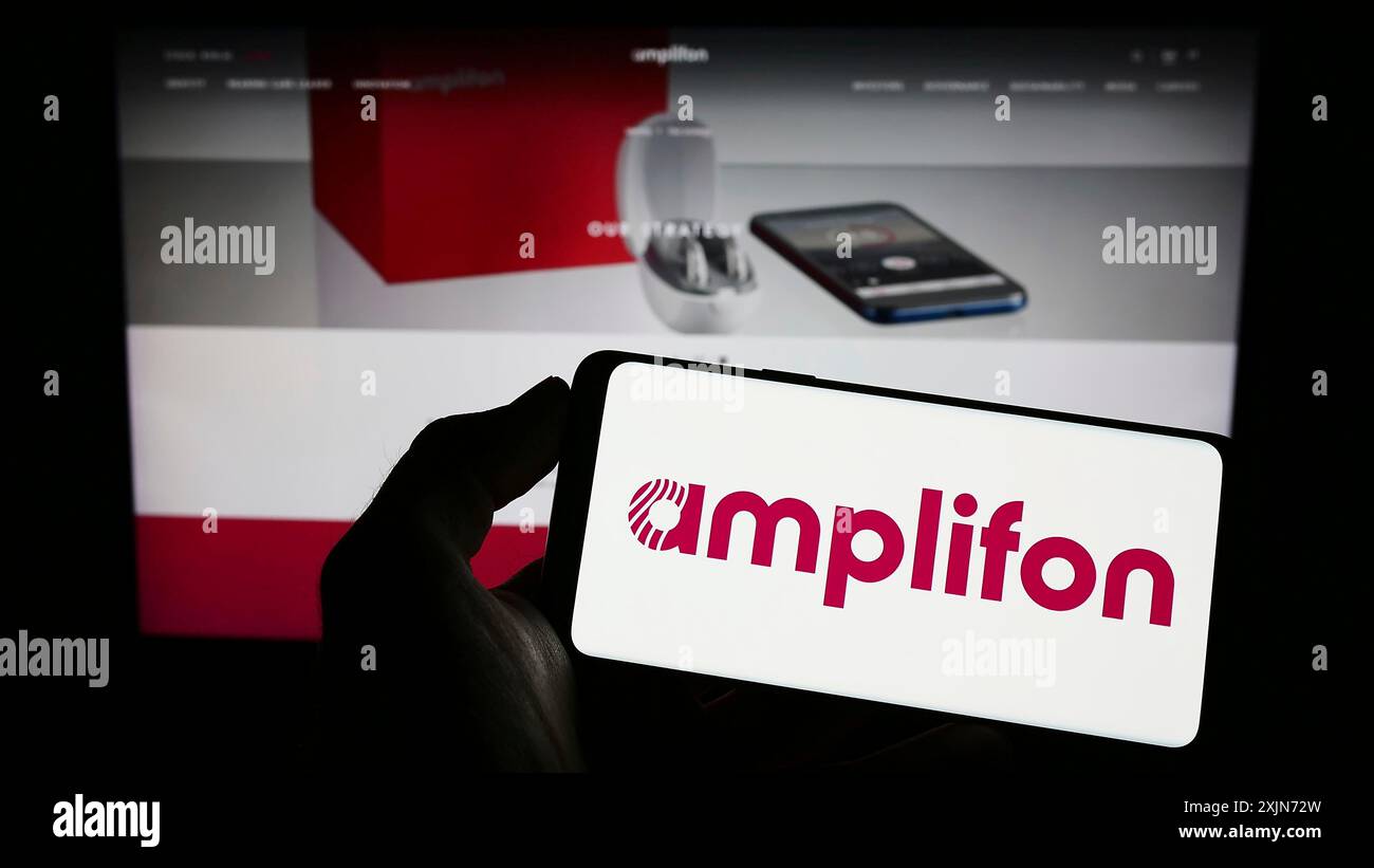 Stuttgart, 25.03.2023: Person mit Mobiltelefon mit Logo des italienischen Hörgeräteunternehmens Amplifon Spa auf dem Bildschirm vor dem Geschäft Stockfoto
