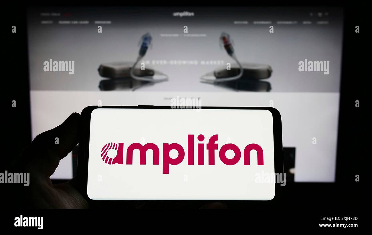 Stuttgart, 25.03.2023: Person mit Smartphone mit Logo des italienischen Hörgeräteunternehmens Amplifon S.p.A. auf dem Bildschirm vor der Website. Stockfoto