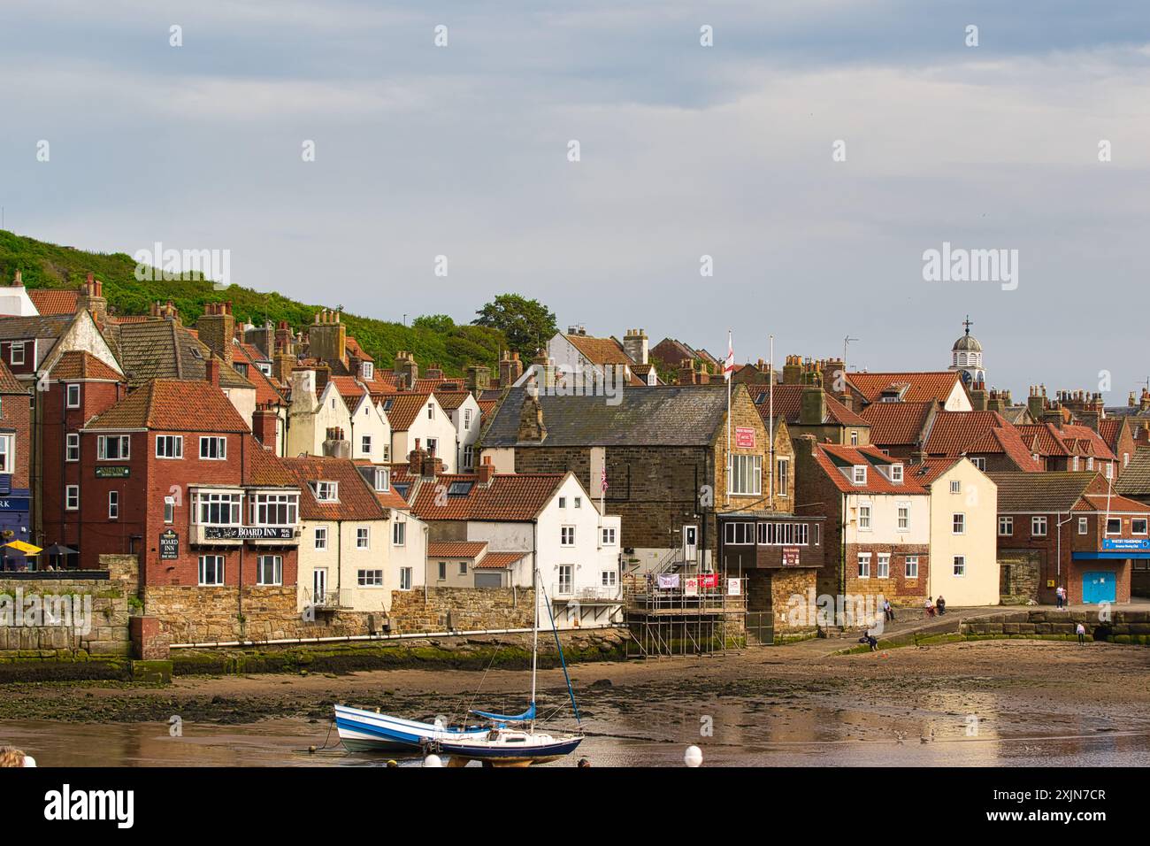 Ein malerisches Küstendorf mit bezaubernden Häusern und Booten, die am Ufer unter einem bewölkten Himmel angedockt sind. Stockfoto