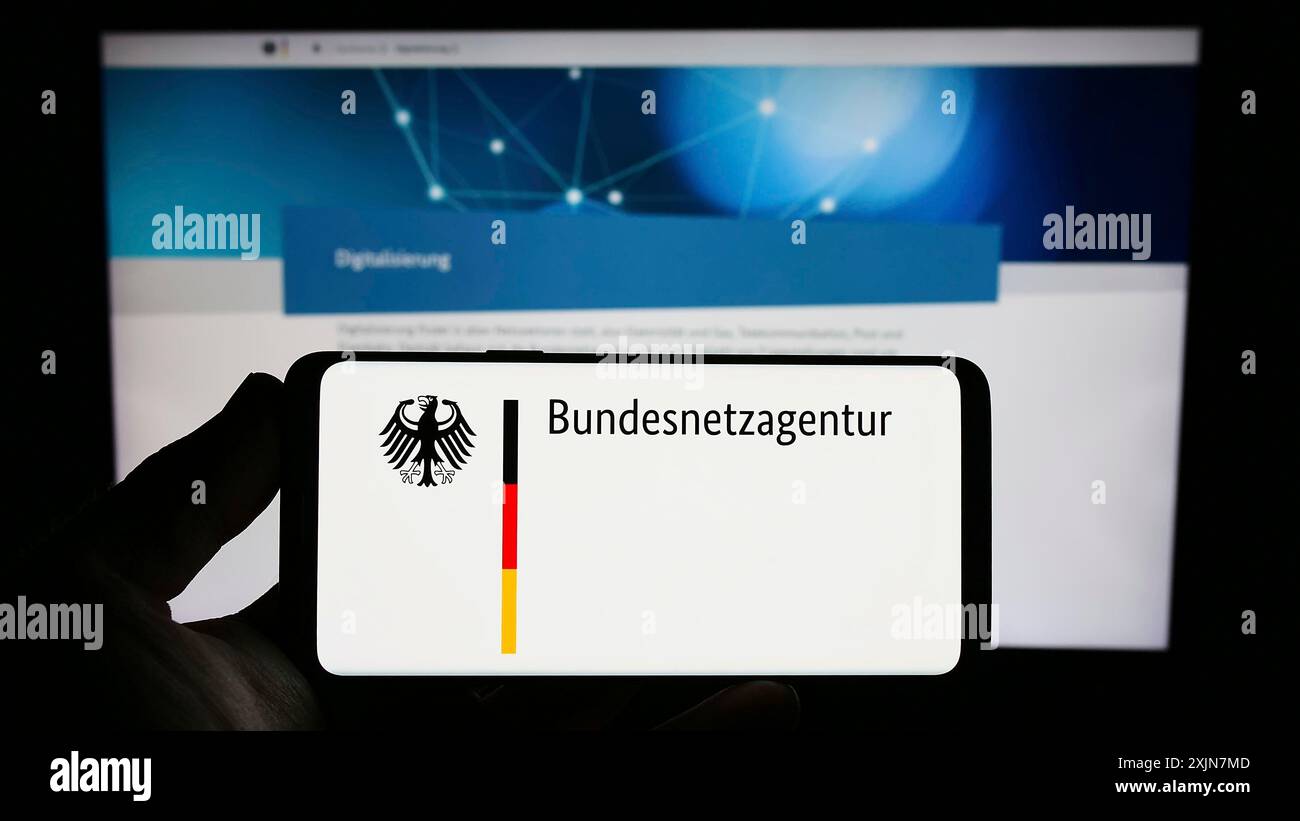 Stuttgart, 24.06.2023: Person, die ein Smartphone mit dem Logo der Bundesnetzagentur (BNetzA) auf dem Bildschirm vor der Website hält. Stockfoto