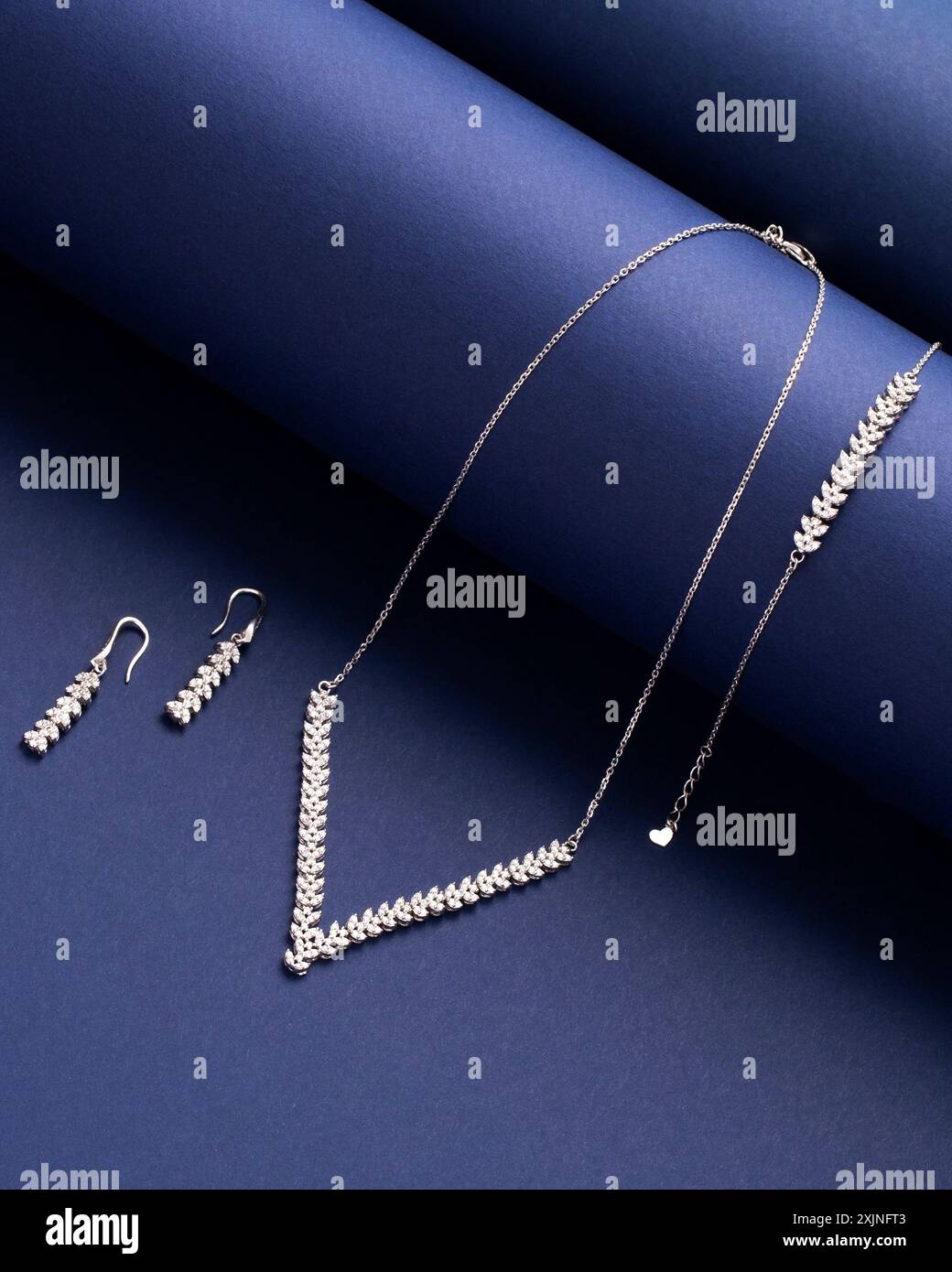 Elegantes Silberschmuck-Set mit Halskette, Armband und Ohrringen auf blauem Hintergrund Stockfoto