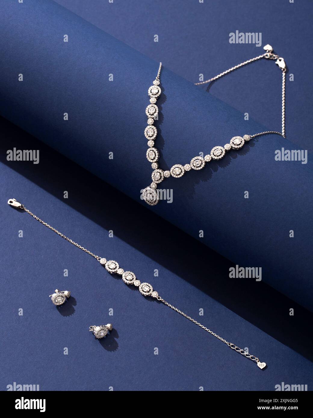 Exquisiter Diamantschmuck auf dunkelblauem Hintergrund, einschließlich Halskette, Armband und Ohrringe. Stockfoto