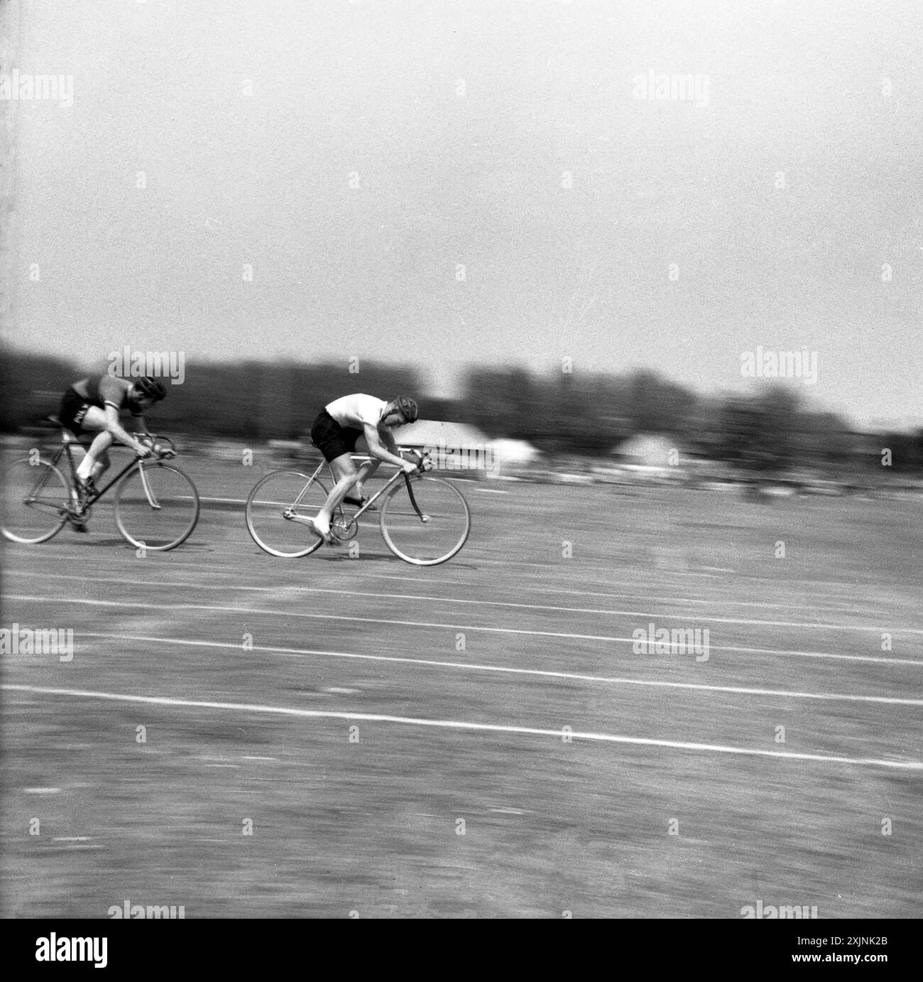 1950er Jahre, Whit Sunday Cycling, zwei männliche Radfahrer, die auf einer Grasstrecke bei einem Outdoor-Radsport-Event in England, Großbritannien, antreten. Stockfoto