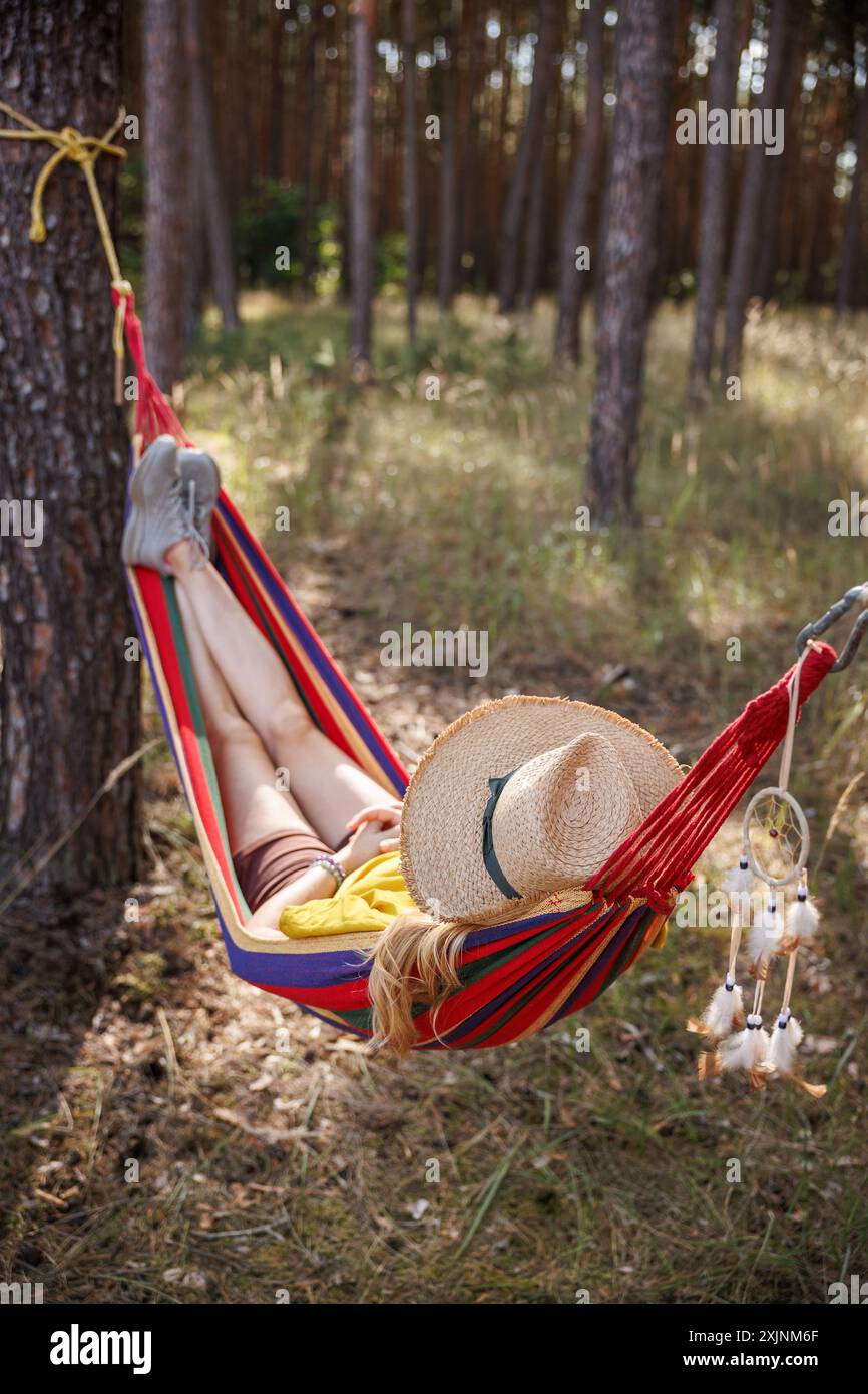 Entspannte Frau mit Hut in Hängematte im Wald. Genießen Sie den Moment und Entspannung im Freien Stockfoto