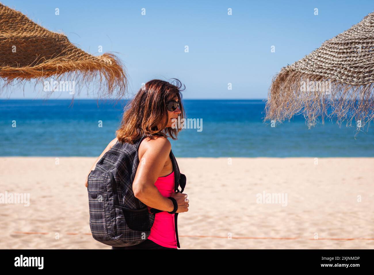 Eine fitte und vitale reife Frau wählt den Ort zum Entspannen am Strand. Aktiver Lebensstil während des Sommerurlaubs in der Algarve, Portugal Stockfoto