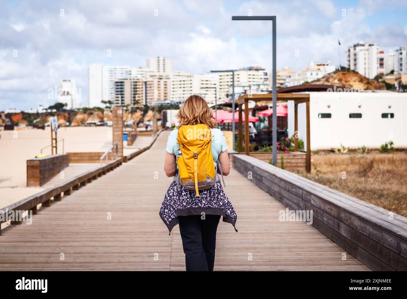 Frau Touristen spaziert entlang der Promenade am Strand in Portimao, Portugal. Alleinreisende Sommerurlaub an der Algarve Stockfoto