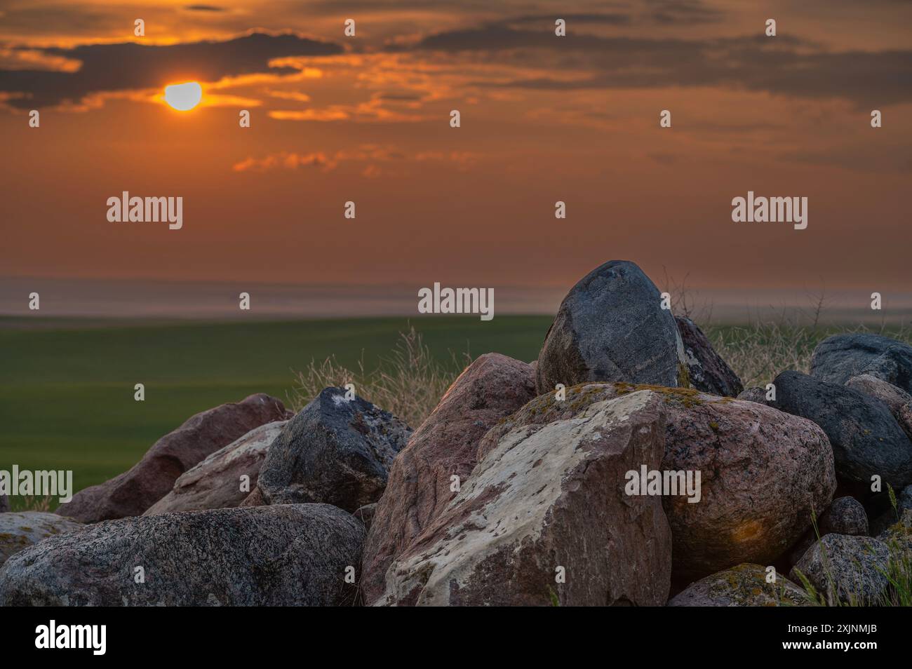 Sonnenuntergang hinter einem Haufen Feldsteine auf der Prärie der Great Sandhills, Saskatchewan, Kanada Stockfoto
