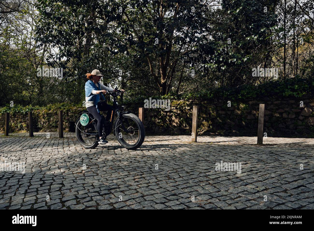 Radfahrer, die auf den malerischen Straßen von Sintra durch die Kopfsteinpflasterpfade fahren, umgeben von üppigem Grün Stockfoto