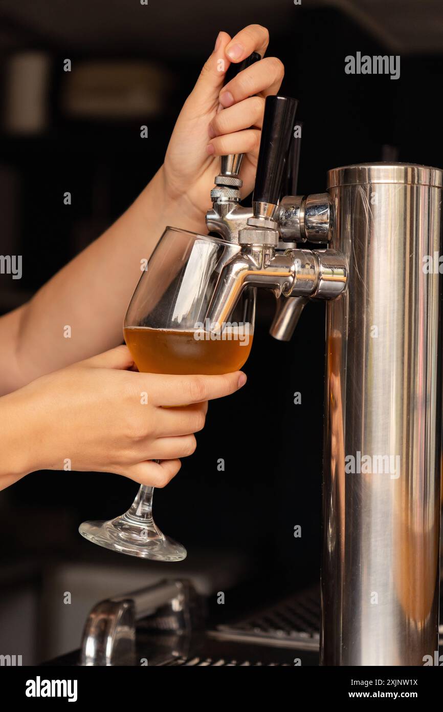 Zarte Hände einer Frau, die in einem Pub frisches Bier aus dem Zapfhahn ins Glas gießt. Stockfoto